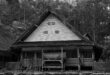Rumah panggung sederhana dengan atap genteng, struktur kayu, dan teras terbuka menonjolkan desain tradisional