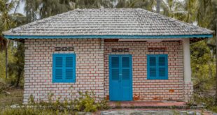 Gambar rumah sederhana berukuran 5x7 meter dengan desain minimalis, atap merah, dan taman kecil di depannya.