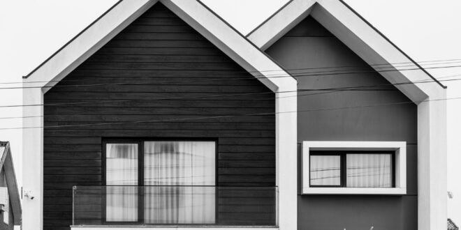 Desain rumah setengah tingkat sederhana dengan tampilan modern, atap miring, dan taman kecil di depan.