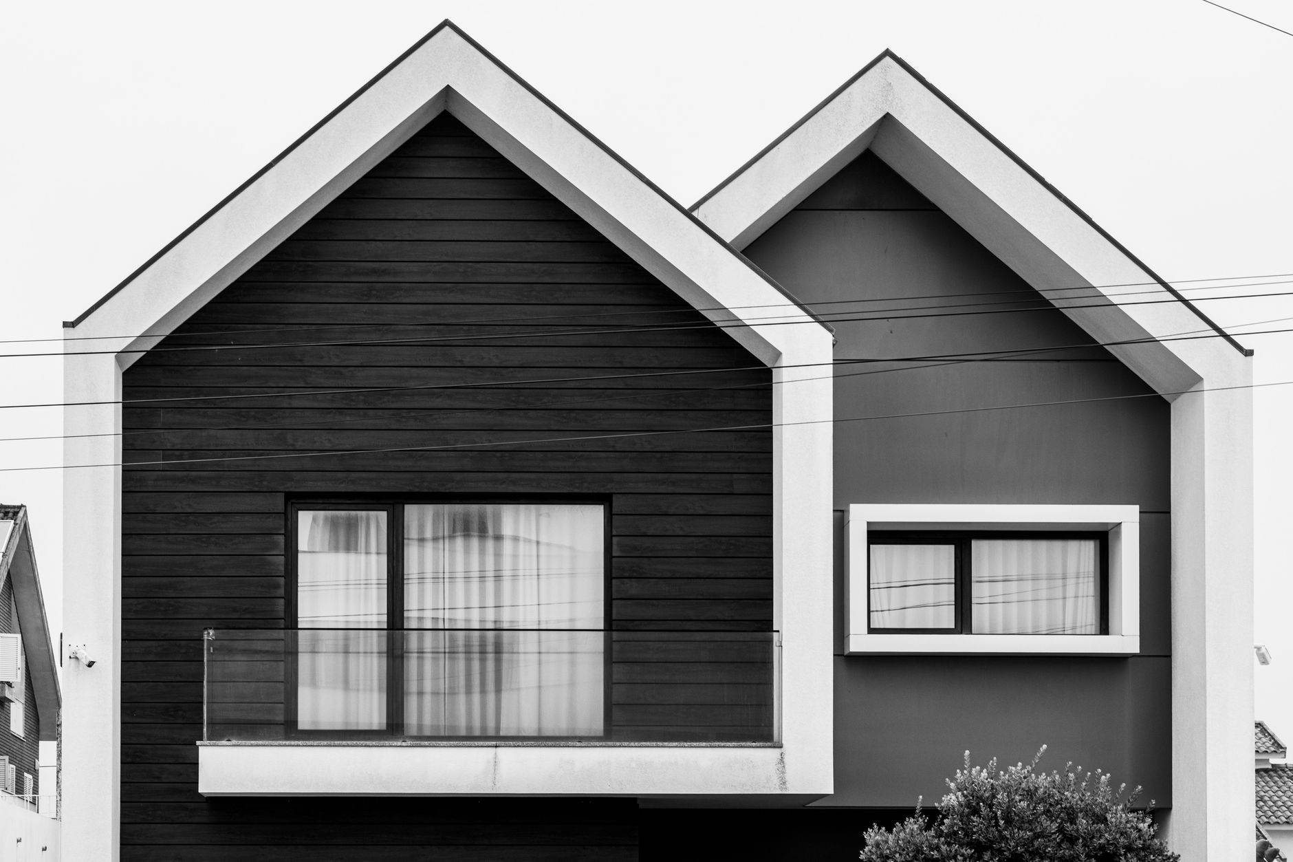 Desain rumah setengah tingkat sederhana dengan tampilan modern, atap miring, dan taman kecil di depan.