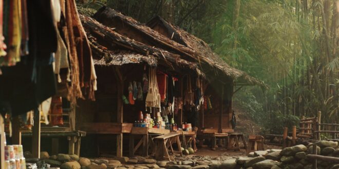 Desain warung sembako sederhana dengan rak kayu, lampu gantung, dan nuansa pedesaan di sebuah kampung.