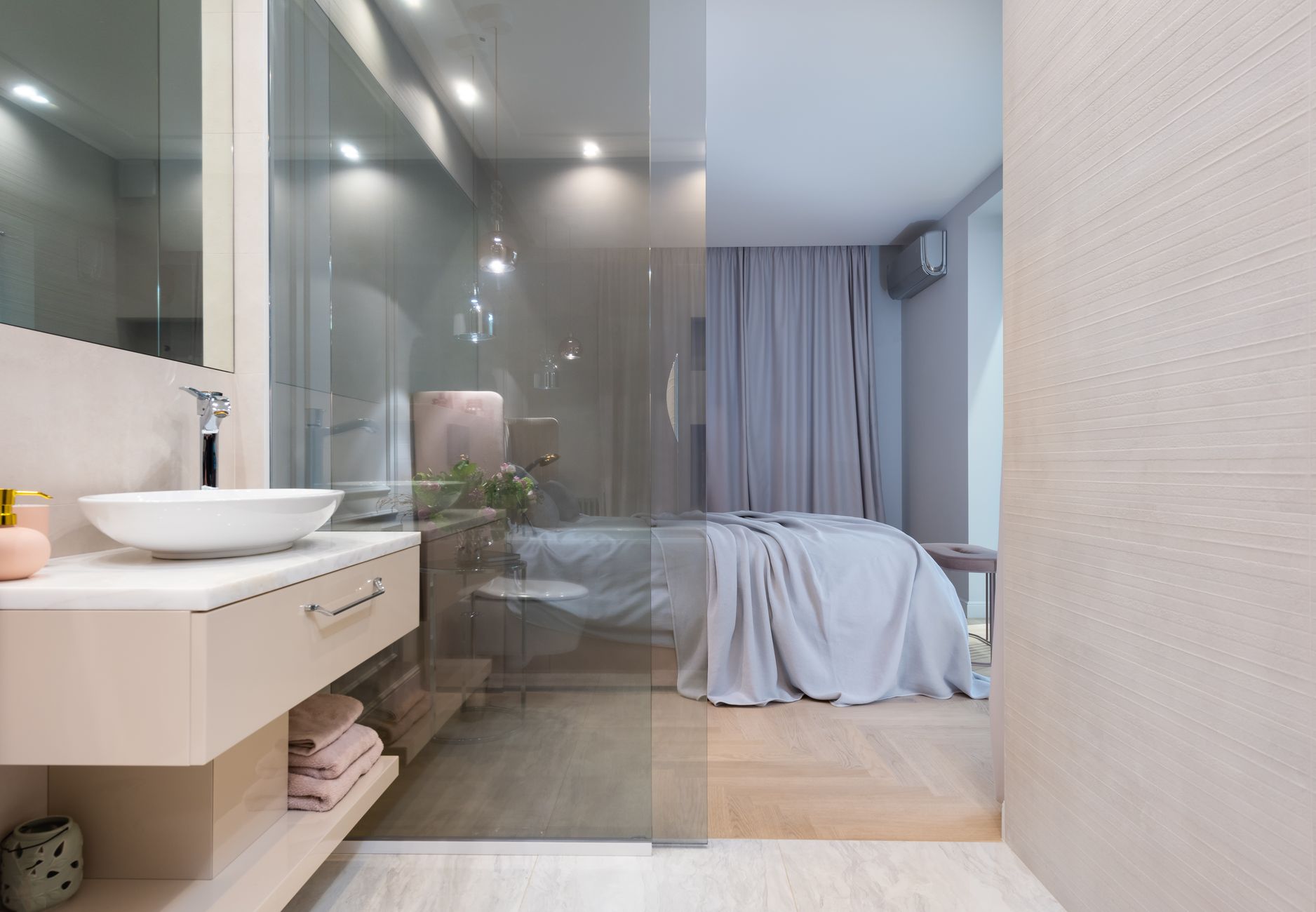 Desain kamar tidur modern dengan kamar mandi dalam simpel, pencahayaan alami, warna netral, dan ruang fungsional