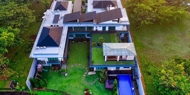 Rumah mewah tiga lantai dengan desain modern, fasad kaca, taman luas, dan pencahayaan alami