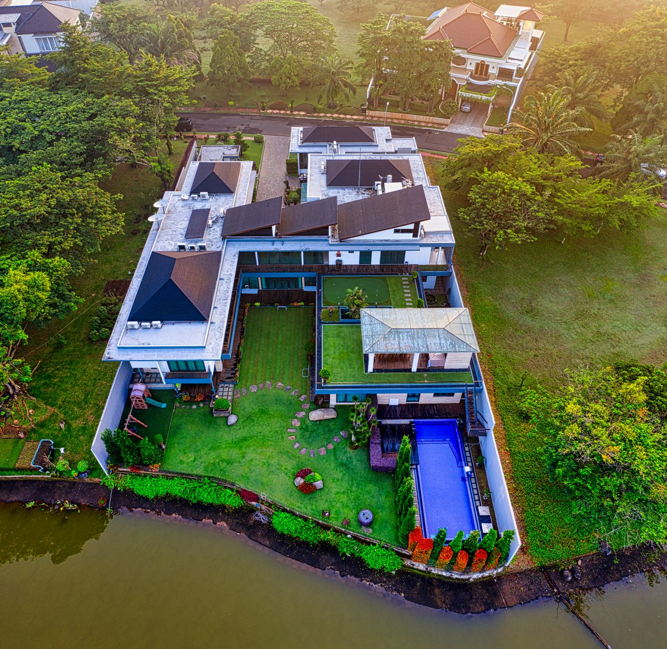 Rumah mewah tiga lantai dengan desain modern, fasad kaca, taman luas, dan pencahayaan alami
