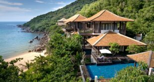 Desain villa sederhana dengan fasad modern, atap datar, dan taman hijau yang menambah kesan alami.