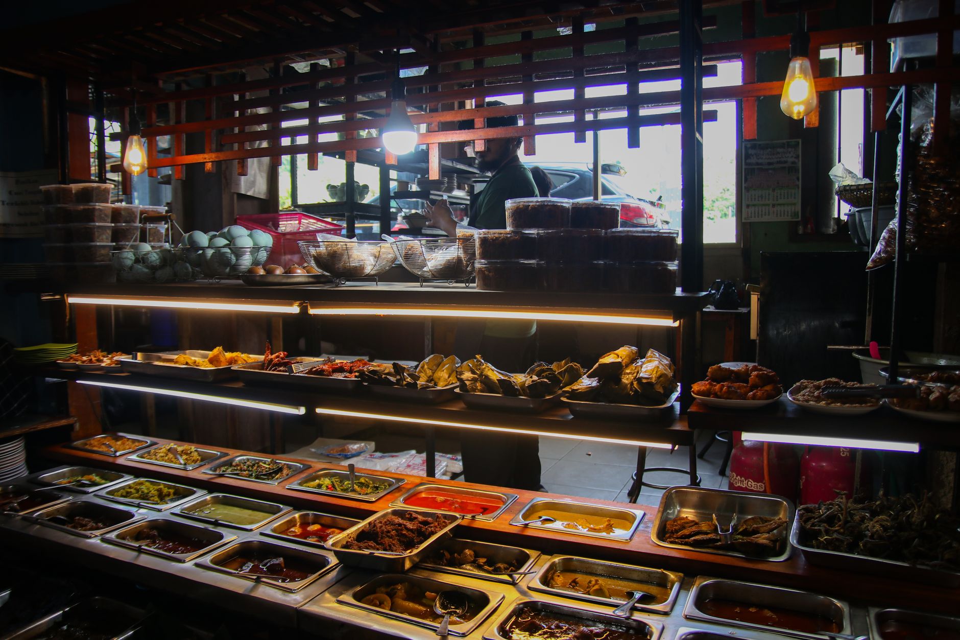 Desain warung makan sederhana dengan tampilan modern, meja kayu, kursi warna cerah, dan pencahayaan alami.