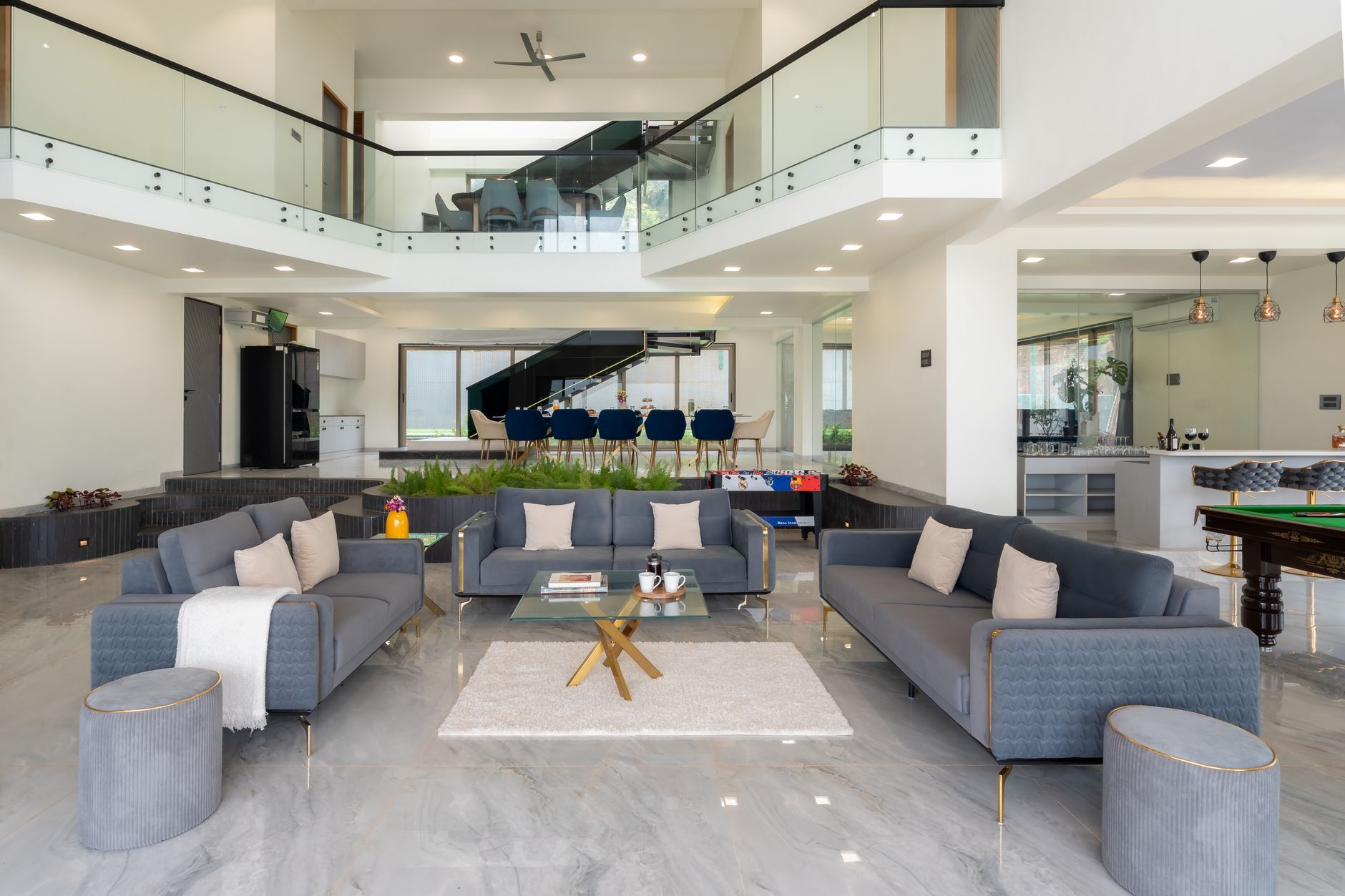Rumah mezzanine sederhana dengan desain minimalis, ruang tamu terbuka, dan balkon kecil menghadap taman.
