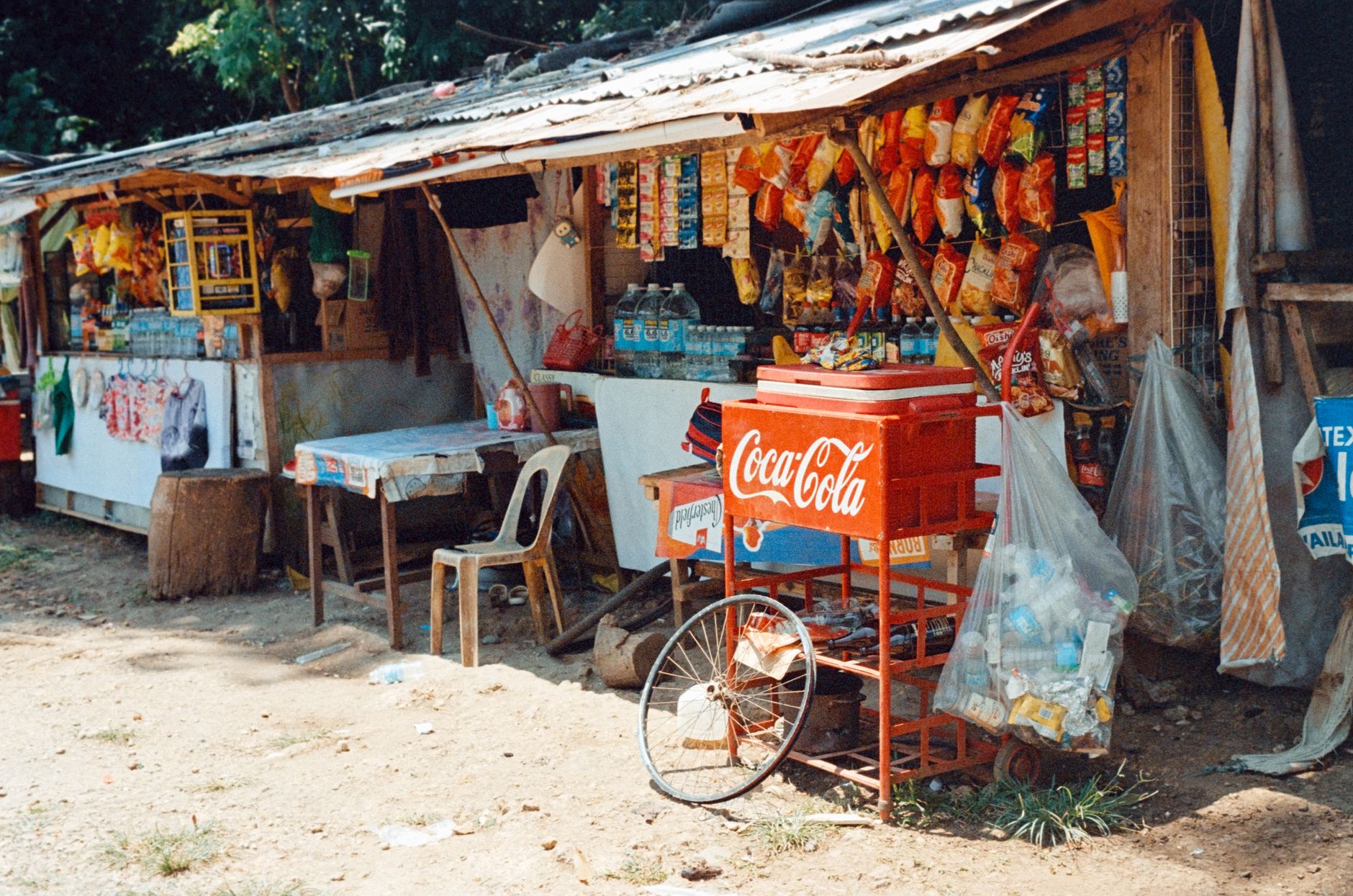 Desain warung sembako sederhana dengan rak kayu, pencahayaan alami, dan nuansa warna cerah di kampung.