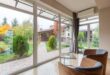 Desain rumah kaca minimalis sederhana dengan struktur transparan dan taman hijau modern.