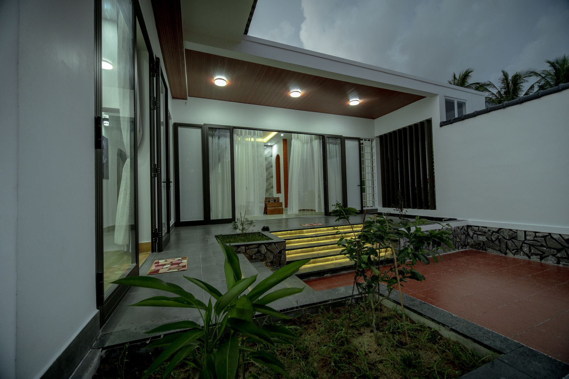 Villa minimalis sederhana dengan desain bersih, tampak modern, dan taman hijau yang menambah kehangatan ruang tamu.